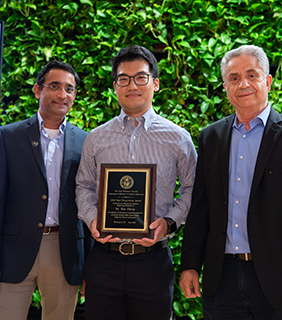 Dr. Hao Zheng accepting award standing between Dr.Subramaniam and Dr. Louri